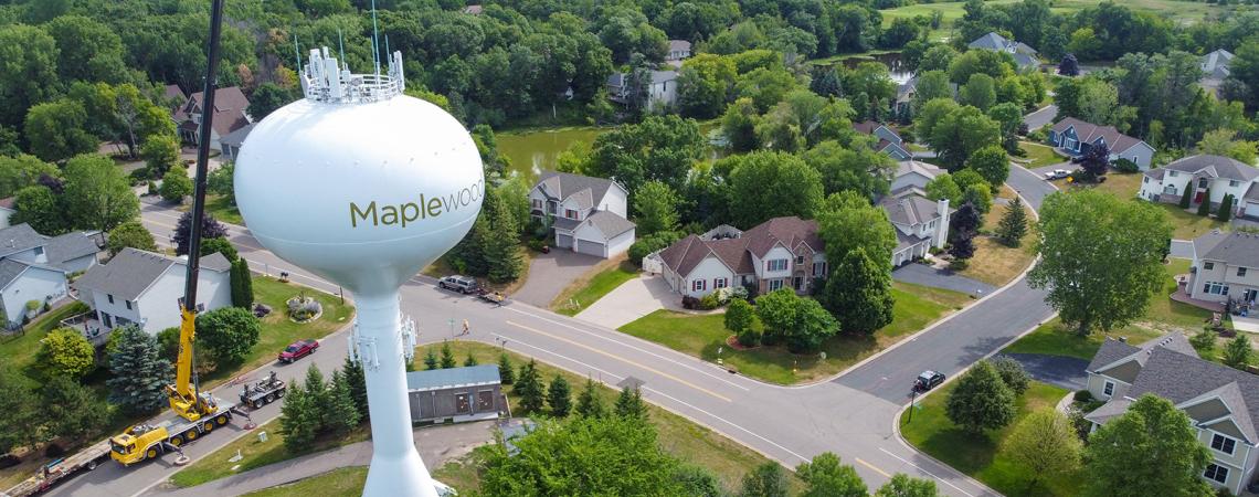 A white water tower labeled Maplewood stands over a suburban neighborhood.